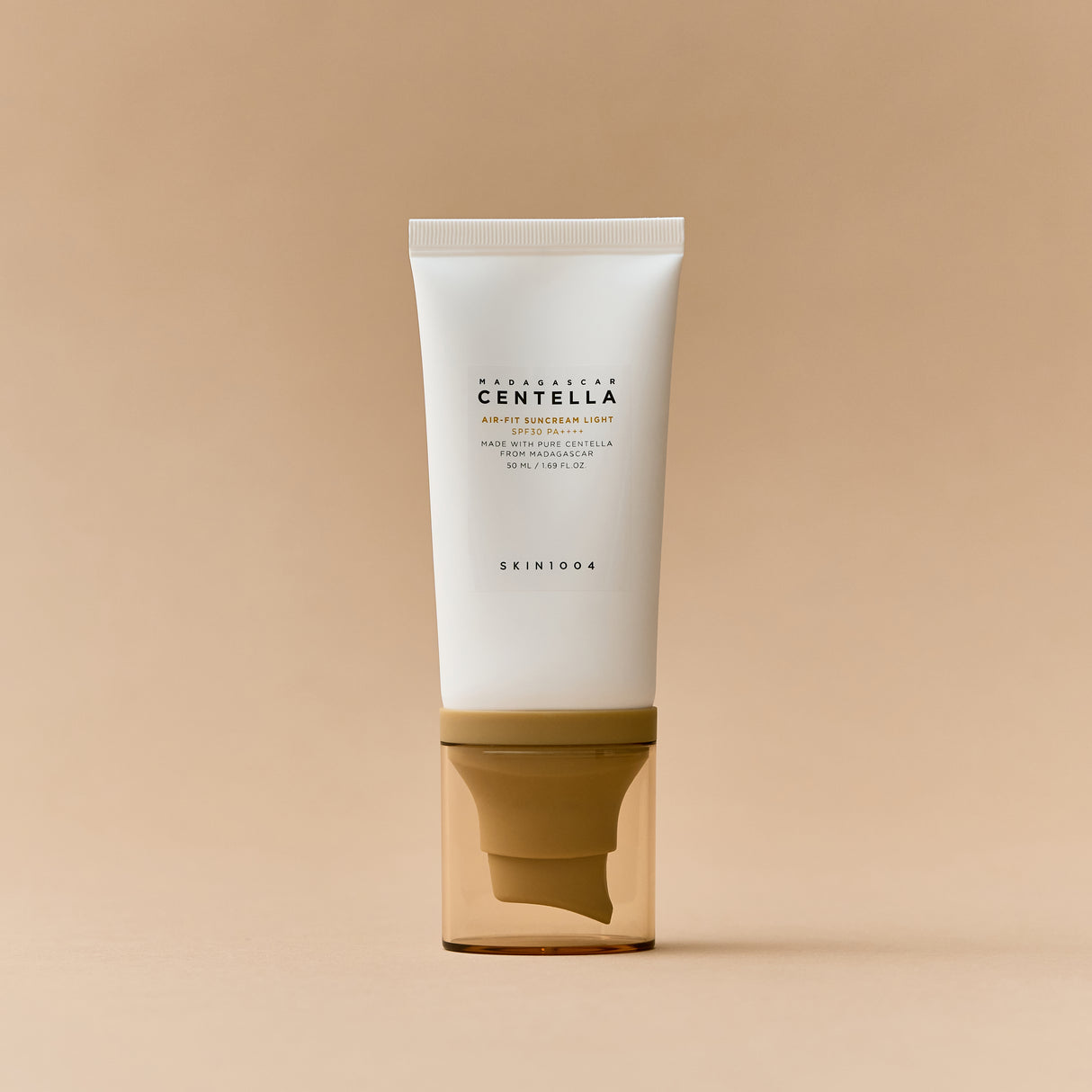 Un tubetto bianco con tappo dorato trasparente del prodotto “Skin1004 Madagascar Centella Air-Fit Suncream Light” è posizionato frontalmente su uno sfondo bianco. Il design è minimal e pulito, con scritte nere centrali.