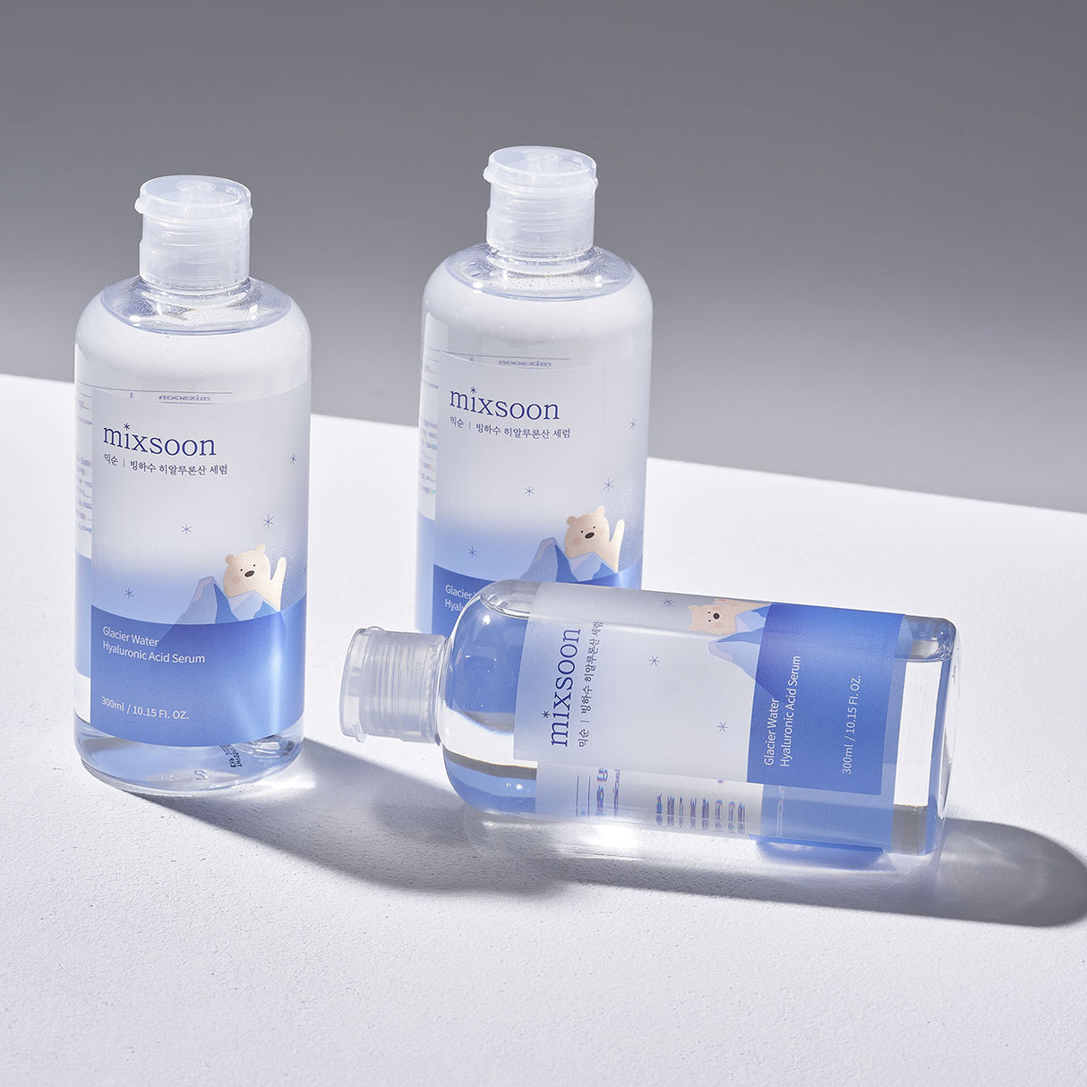 Glacier Water hyaluronic Acid Serum tre flaconi trasparenti con etichetta blu con orso polare disegnato con ghiacciaio su sondo bianco grigio