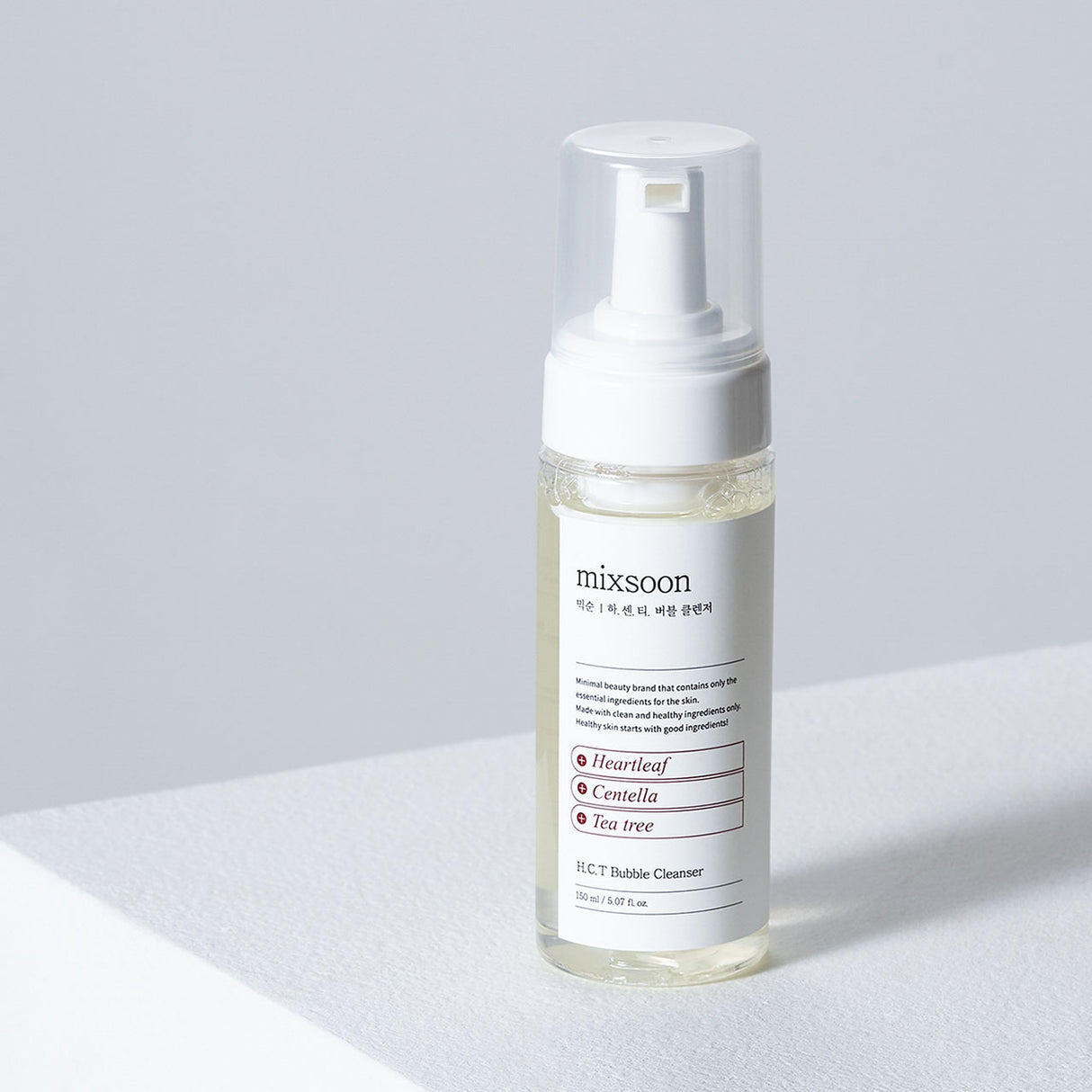 "Flacone del detergente Mixsoon H.C.T. Bubble Cleanser da 150 ml appoggiato su una superficie bianca, con sfondo grigio chiaro minimalista."
