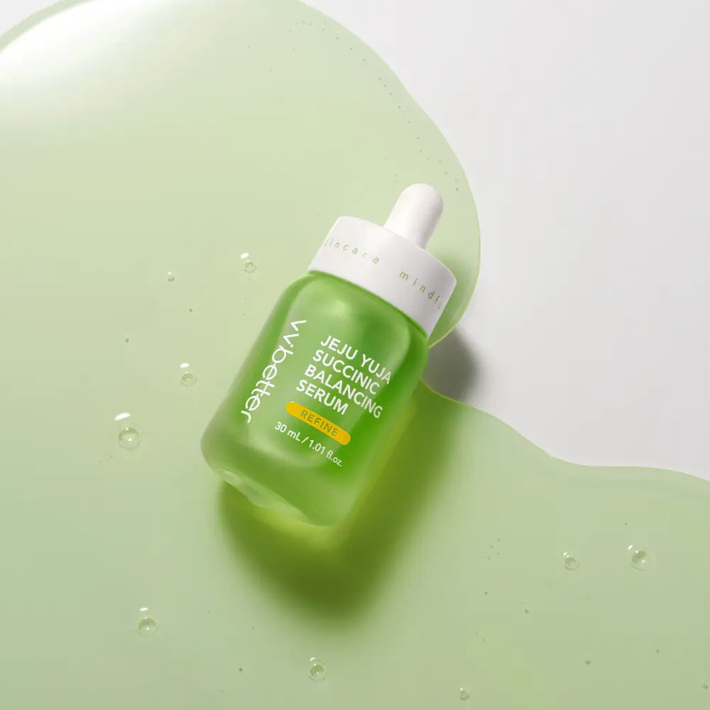 Immagine prodotto del siero viso Jeju Yuja Succinic Balancing Serum di Whalette, flacone contagocce verde posato su superficie con texture liquida. Siero illuminante e riequilibrante formulato con estratto di yuja di Jeju e acido succinico, ideale per migliorare luminosità e uniformità della pelle.