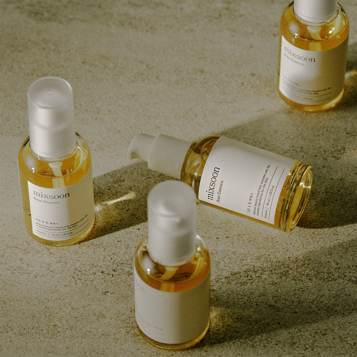 Quattro bottiglie di Mixsoon Bifida Essence disposte artisticamente su una superficie chiara, con luce naturale e packaging elegante.