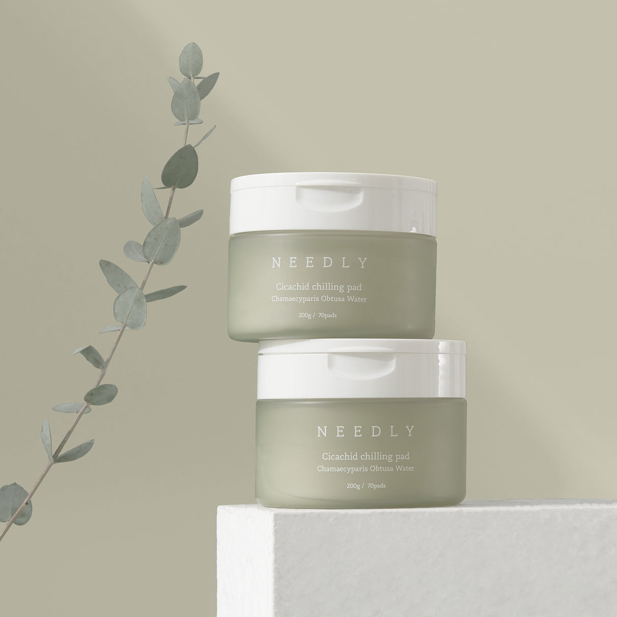 Due vasetti verde oliva con tappo bianco del prodotto NEEDLY Cicachid Chilling Pad, con testo descrittivo “Chamaecyparis Obtusa Water” e indicazione di contenuto: 200 g / 70 pads, su sfondo verde oliva