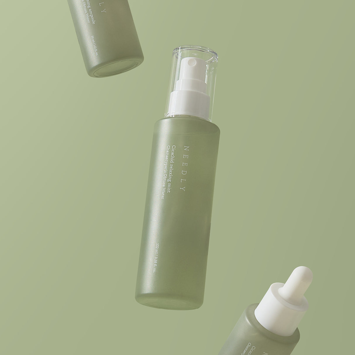 Tre flaconi della Needly Cicachid Relaxing Mist fluttuano su uno sfondo verde chiaro. Uno dei flaconi è dotato di erogatore spray trasparente, mentre un altro presenta un contagocce bianco opaco.