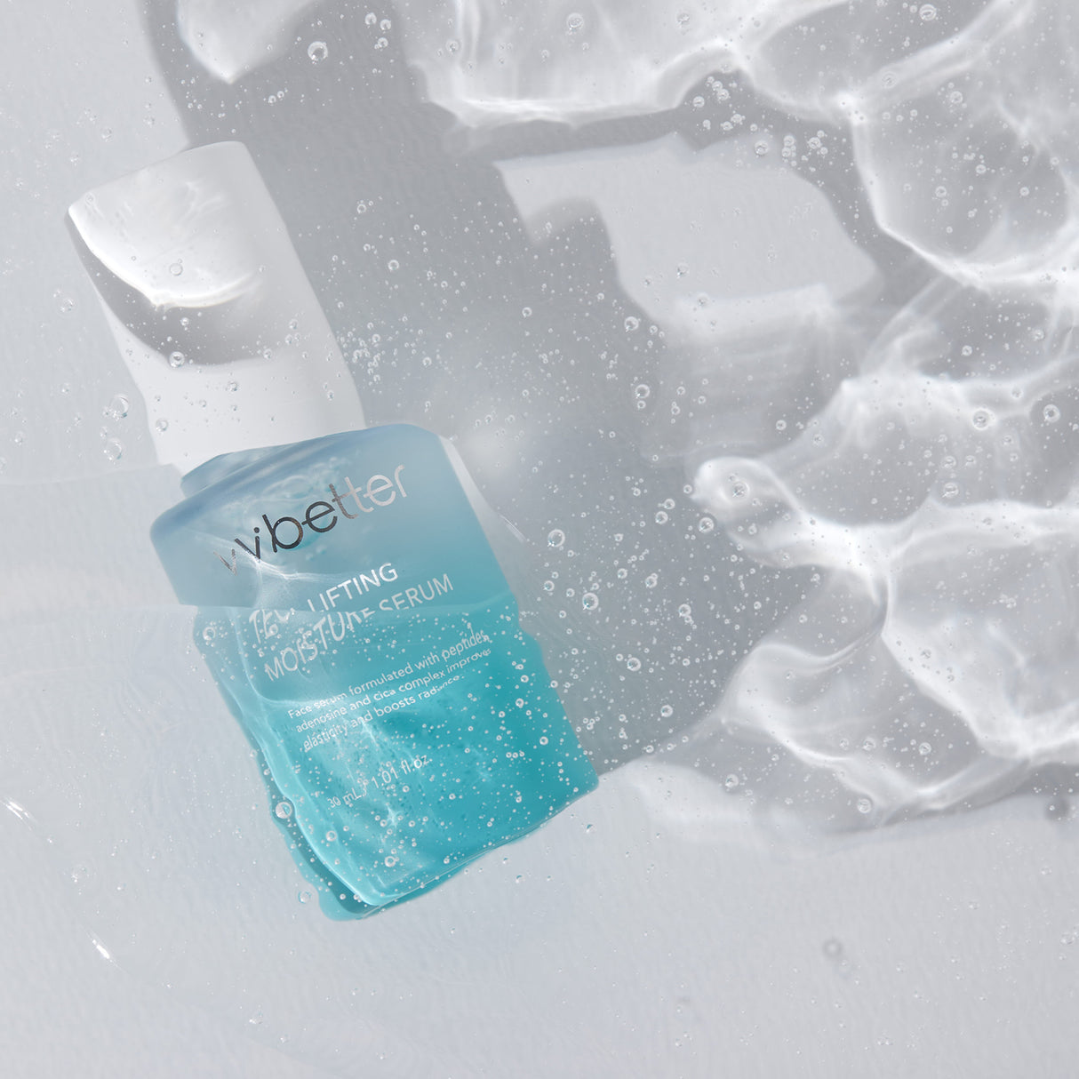 Flacone azzurro del siero vvbetter TECA Lifting Moisture da 30ml immerso in acqua con riflessi e bolle su sfondo chiaro