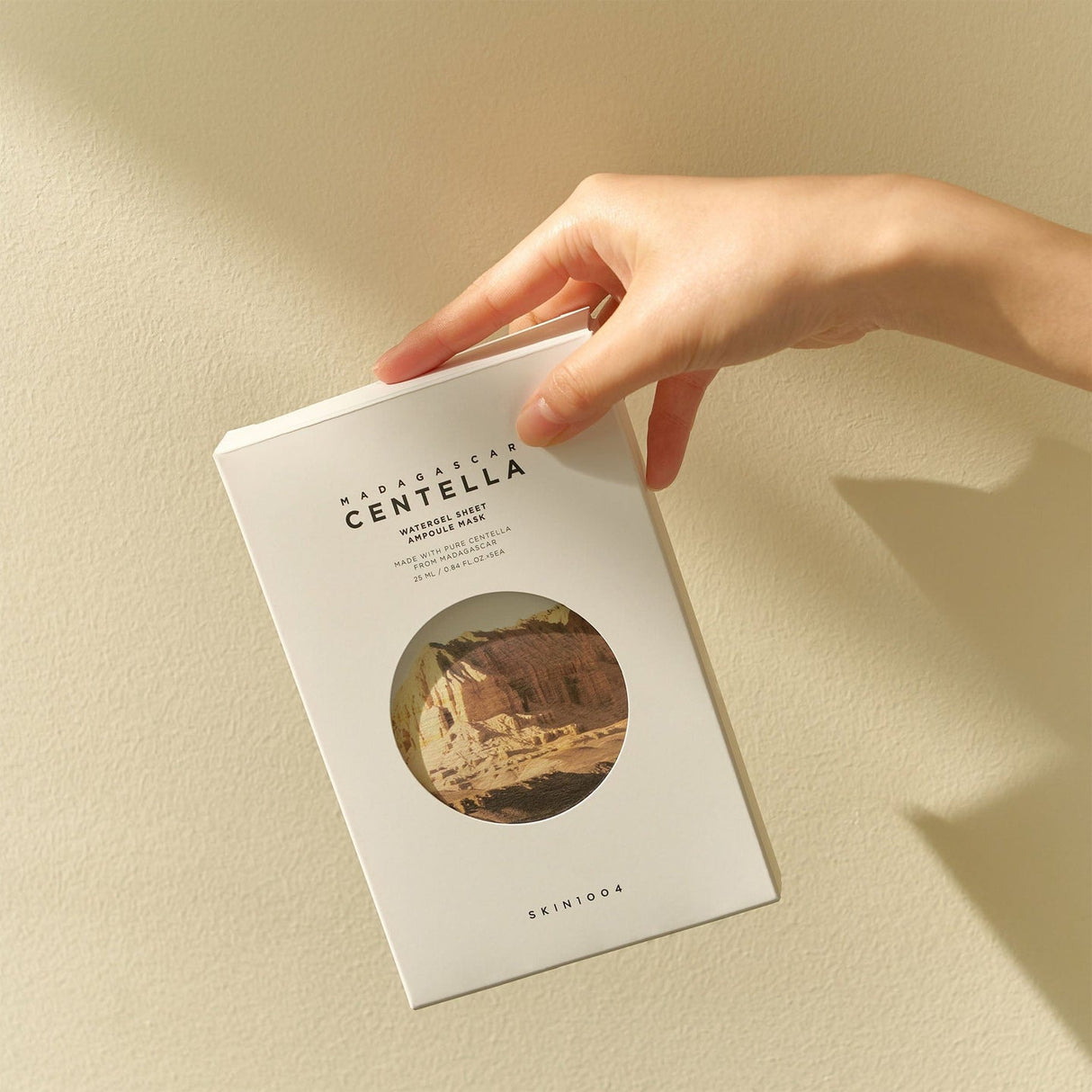 Confezione di SKIN1004 Madagascar Centella sheet mask tenuta in mano su sfondo chiaro