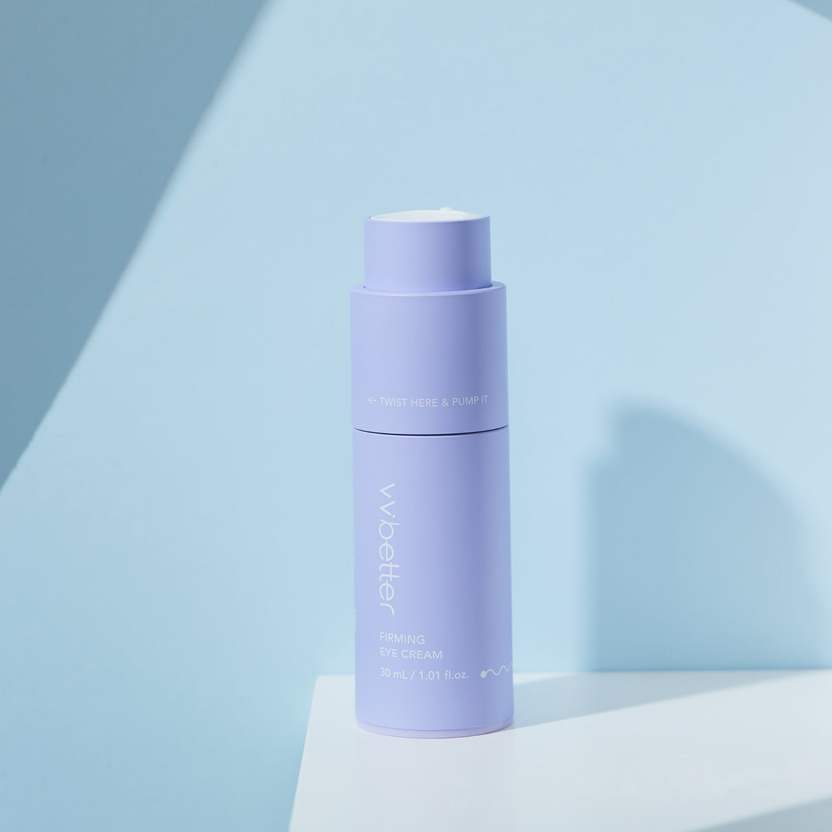 Flacone color lavanda del vvbetter Firming Eye Cream da 30 ml / 1.01 fl.oz., posizionato su una superficie bianca contro uno sfondo neutro, con la scritta “TWIST HERE & PUMP IT” visibile sulla parte superiore.