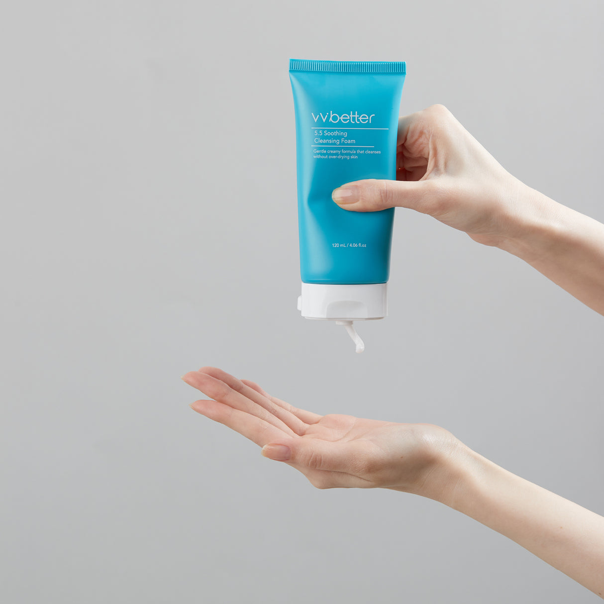 vvbetter soothing cleansing foam flacone azzurro in mano su sfondo grigio con crema che esce