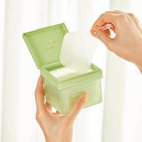 Mani che aprono una confezione verde di dischetti tonici coreani (toner pad)