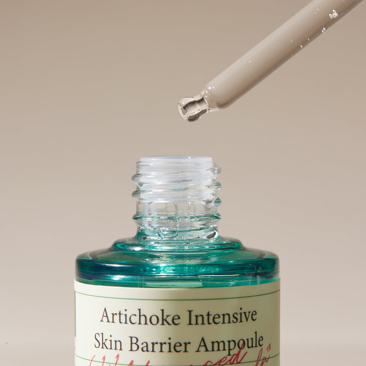  Dettaglio ravvicinato del contagocce mentre rilascia una goccia sopra il flacone aperto del AXIS-Y Artichoke Intensive Skin Barrier Ampoule. Il liquido trasparente enfatizza la texture fluida del siero. Sfondo beige neutro.

