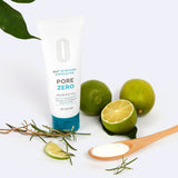 Tubo dell’esfoliante BE THE SKIN PORE ZERO BHA+ 30 Second Exfoliator posizionato accanto a lime interi e tagliati, rametti di rosmarino e un cucchiaio di legno con polvere bianca, su sfondo bianco chiaro.

