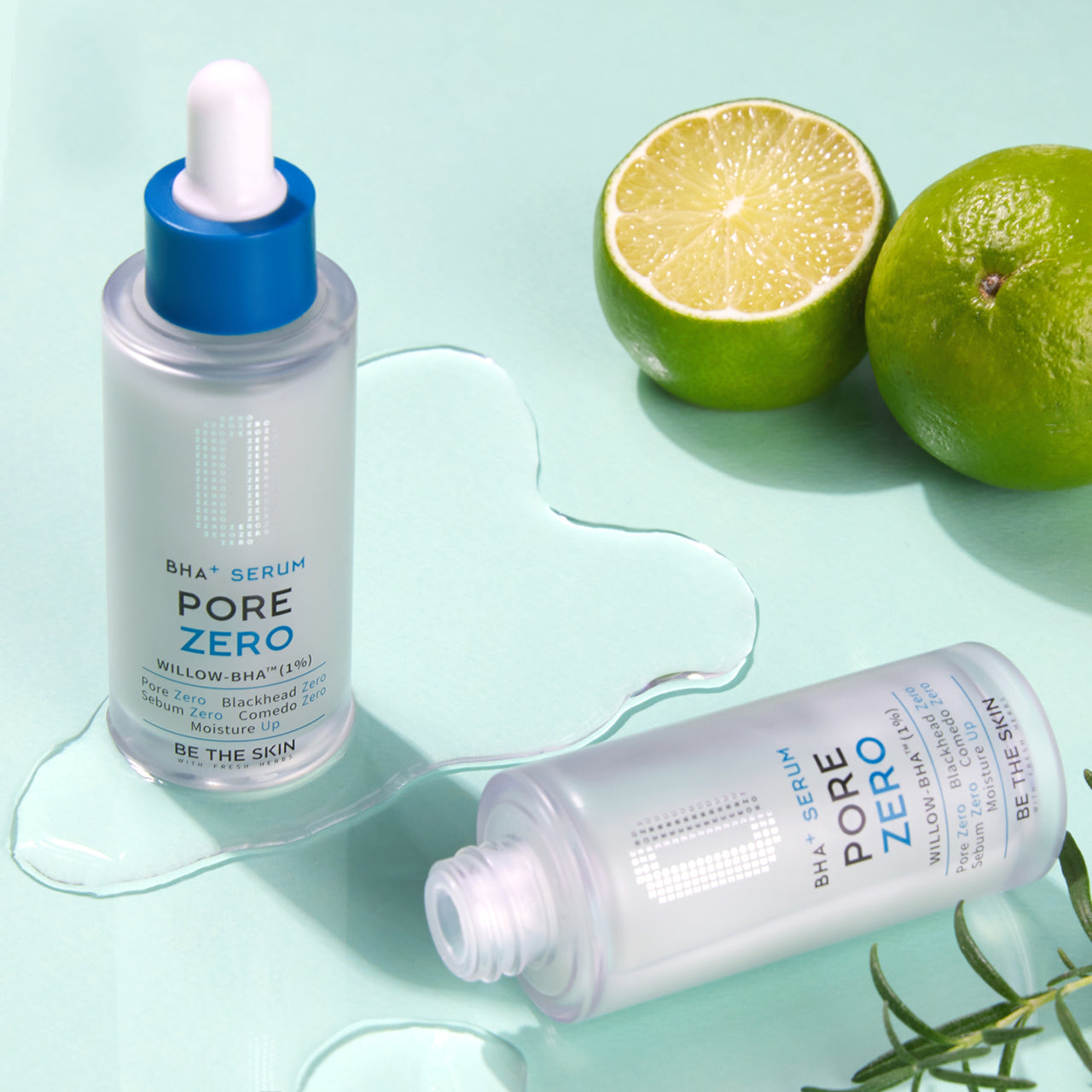 Due flaconi del siero BE THE SKIN PORE ZERO BHA+ su sfondo verde menta, uno in piedi e l’altro sdraiato con tappo svitato, affiancati da lime freschi tagliati e gocce d’acqua che evocano freschezza e idratazione.