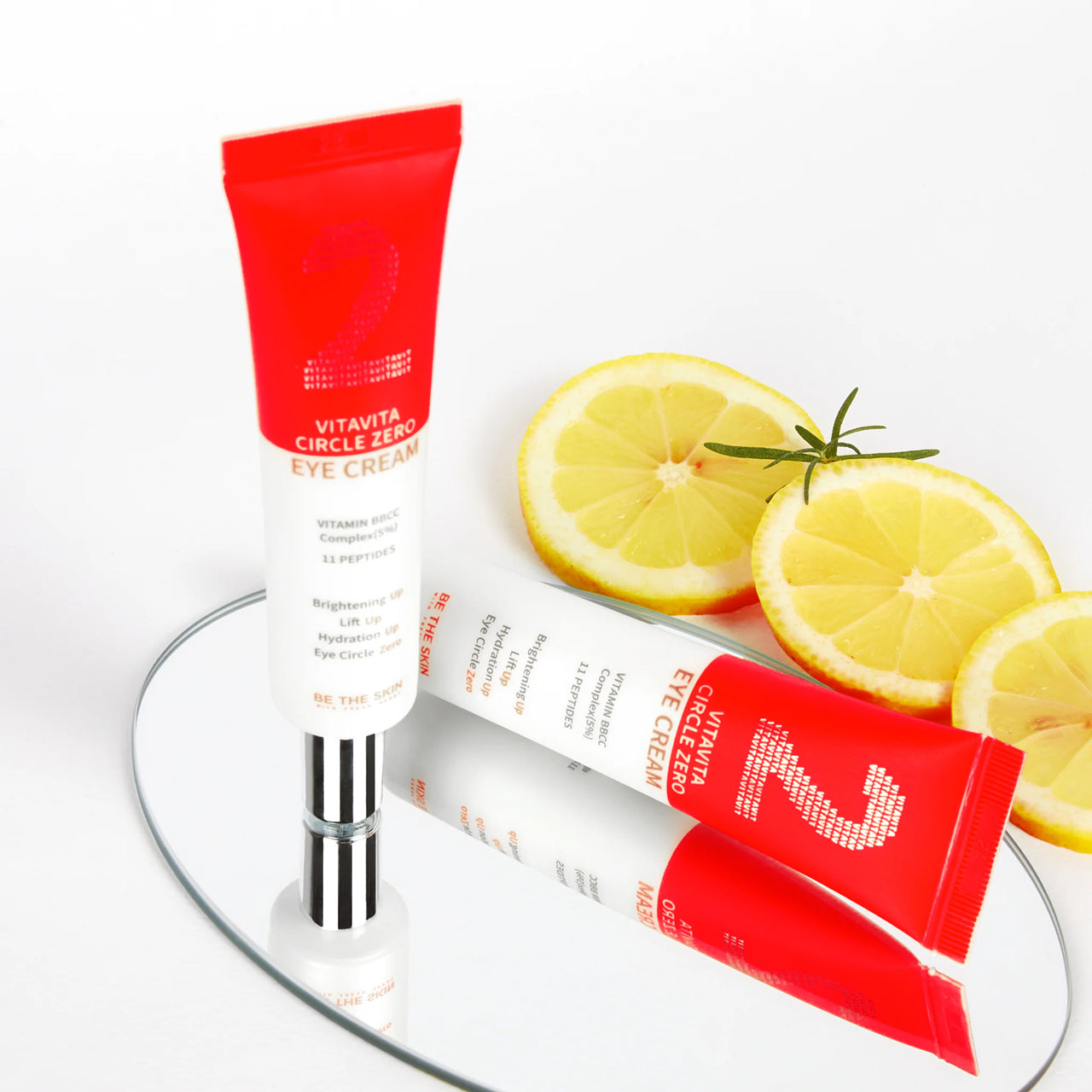 Tubo e confezione della crema contorno occhi VITAVITA CIRCLE ZERO EYE CREAM di BE THE SKIN, posizionati verticalmente su sfondo bianco con fette di limone e foglie di rosmarino