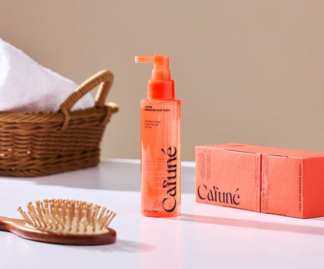 Cafuné Enhancer Hair Tonic tonico cute anticaduta spray arancione con confezione e spazzola su sfondo neutro