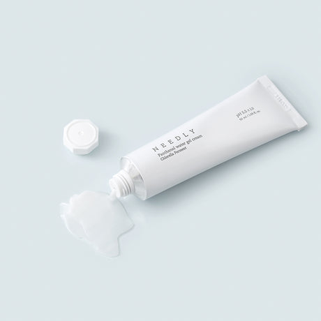 Un tubetto bianco di Needly Panthenol Water Gel Cream con tappo svitato e crema trasparente-gel fuoriuscita su una superficie azzurra, mostrata in un contesto minimal e fresco