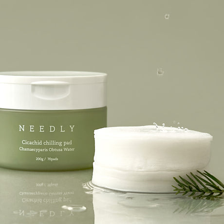 Vasetto verde oliva con tappo bianco del prodotto NEEDLY Cicachid Chilling Pad, con testo descrittivo “Chamaecyparis Obtusa Water” e indicazione di contenuto: 200 g / 70 pads, su sfondo bianco.