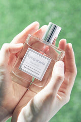 Profumo coreano Ahro Like Lilac tenuto tra le mani all’aperto con flacone in vetro trasparente e tappo argentato.