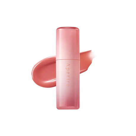 Lip tint Aperire con packaging rosa sfumato posizionato davanti a una texture nude rosata lucida su sfondo chiaro