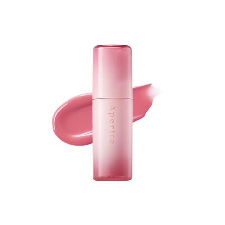 Lip tint Aperire con packaging rosa sfumato posizionato davanti a una texture rosa glossy su sfondo chiaro
