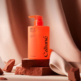 Flacone shampoo Cafuné arancione posizionato su set fotografico con drappeggio tessile e pietre naturali, visual brand hair care coreano.
