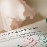 Primo piano ravvicinato dell’etichetta del siero AXIS-Y Dark Spot Correcting Glow Serum, con un morbido petalo rosa sfocato in primo piano che conferisce un tocco poetico e delicato all’immagine.

