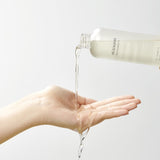 Flacone di Mixsoon Bean Cleansing Oil che versa l’olio detergente sul palmo della mano su sfondo neutro