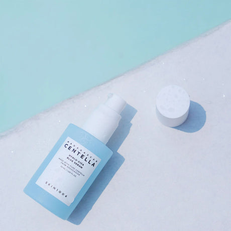 Flacone azzurro da 50ml con tappo bianco del prodotto SKIN1004 Centella, adagiato su superficie chiara con il tappo appoggiato a fianco