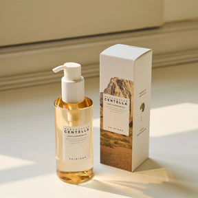 Flacone del detergente SKIN1004 Madagascar Centella Light Cleansing Oil da 200ml con pompa bianca accanto alla confezione originale, posizionati su una superficie beige con luce naturale.