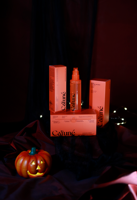 prodotti per capelli skincare coreana cafunè con confezioni arancioni esposti su tessuto nero con zucca decorativa per halloween