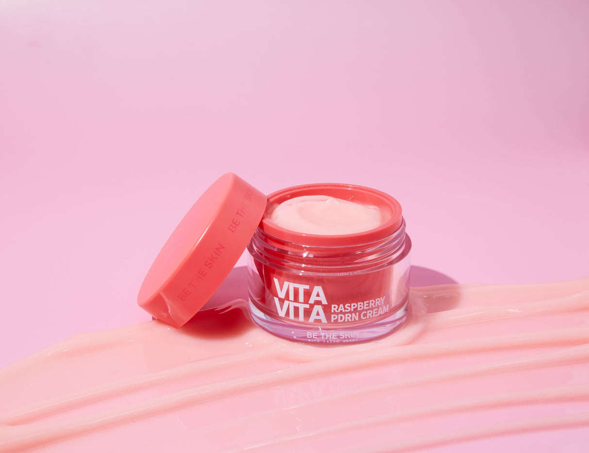 Barattolo aperto di Vita Vita Raspberry PDRN Cream Be The Skin con tappo appoggiato su sfondo rosa