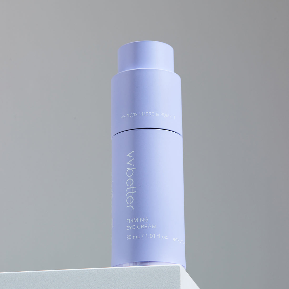 Flacone color lavanda del vvbetter Firming Eye Cream da 30 ml / 1.01 fl.oz., posizionato su una superficie bianca contro uno sfondo neutro, con la scritta “TWIST HERE & PUMP IT” visibile sulla parte superiore.